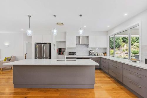 a large white kitchen with a large island in it at Tarragal by Coast Hosting in Terrigal