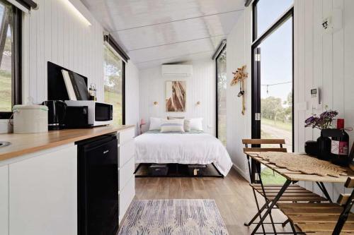 a white bedroom with a bed and a table at Acre Away by Tiny Away in Kangaroo Ground