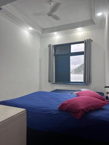 una camera da letto con un letto blu e una finestra di Pousada Recanto da Prainha a São Vicente