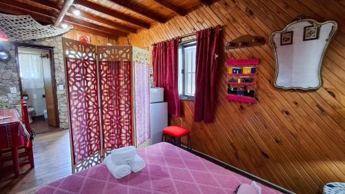 Un dormitorio con una cama rosa y una pared de madera en Cabaña 'Te para Tres' Merlo San Luis, en Merlo