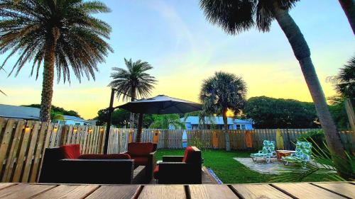 a patio with chairs and an umbrella and palm trees at Beachside home, less than 500 steps to beach, oasis yard in Saint Augustine Beach