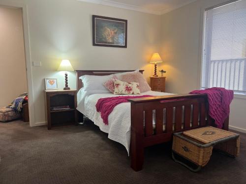 a bedroom with a bed with pink sheets and pillows at Blue Iris in Penguin