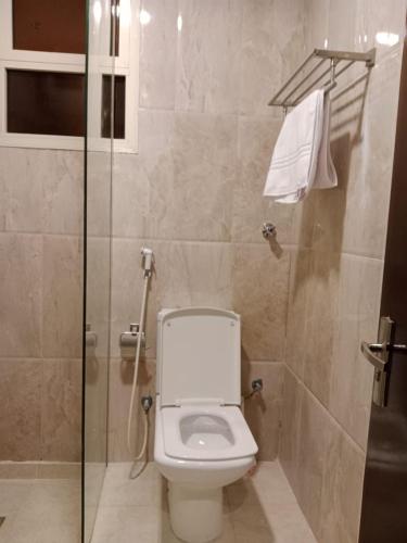 a bathroom with a toilet and a glass shower at فندق اوتاد البدر الششه in Al Khansāk