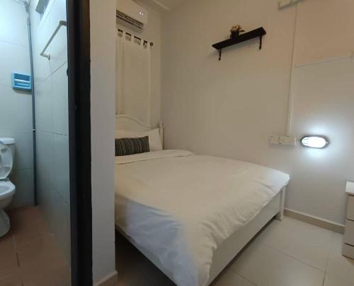 een kleine slaapkamer met een wit bed en een toilet. bij Melaka Kota Home in Melaka