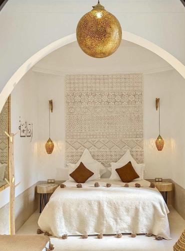 um quarto com uma cama grande e um lustre dourado em Maison al Andalus em Essaouira