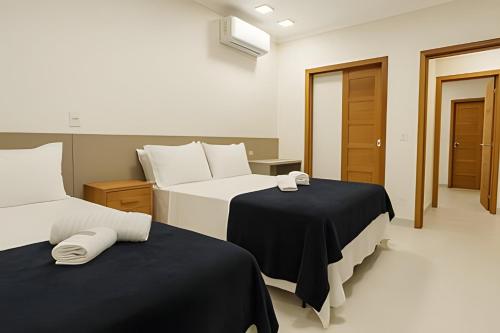 una camera d'albergo con due letti con lenzuola bianche e nere di Itaparica Beira-Mar [Confortável e Pé na areia] a Vila Velha