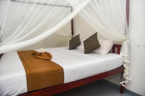 um quarto com uma cama com cortinas brancas em The Golden Sand Villa in Unawatuna em Unawatuna