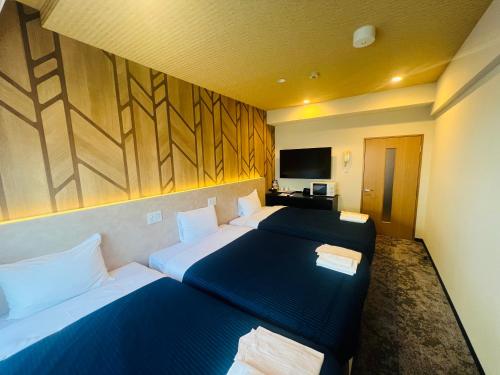a hotel room with two beds and a television at HOTEL LiVEMAX BUDGET Nagoya in Nagoya