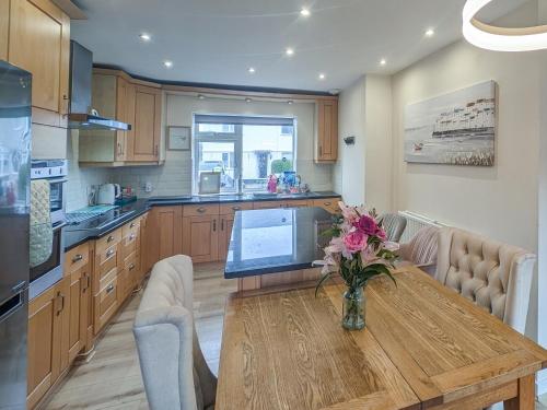 a kitchen with a wooden table with a vase of flowers on it at Afallon in Conwy