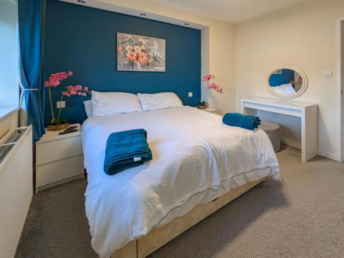 a bedroom with a large bed with a blue wall at Afallon in Conwy