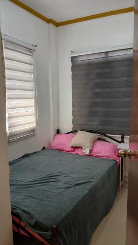 Un dormitorio con una cama con cabecero gris y sábanas rosas. en Mel's Place Batangas City Unit 4 Sta Rita 2 Bedroom House w Free Parking, Google TV WIFI 4 Guests, en Batangas