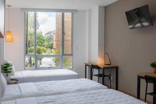Dos camas en una habitación con ventana. en Edificio Plaza U Wellness, en Pereira