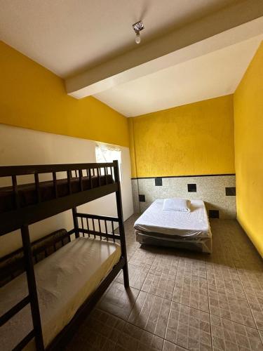 een slaapkamer met 2 stapelbedden en een gele muur bij Pousada Ícone dos Mares in Mongaguá
