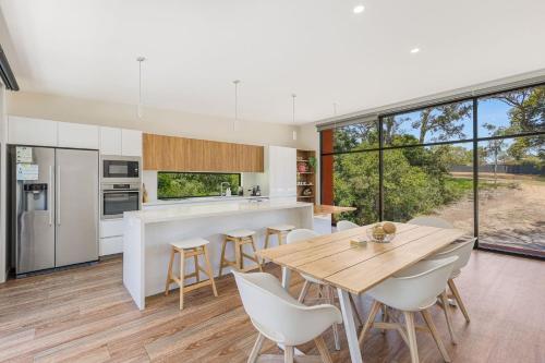 an open kitchen and dining room with a wooden table and chairs at Sirocco on Main in Merimbula