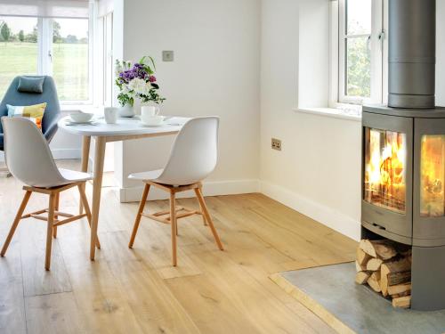 een woonkamer met een open haard en een tafel en stoelen bij Swallows Nest in Bibury
