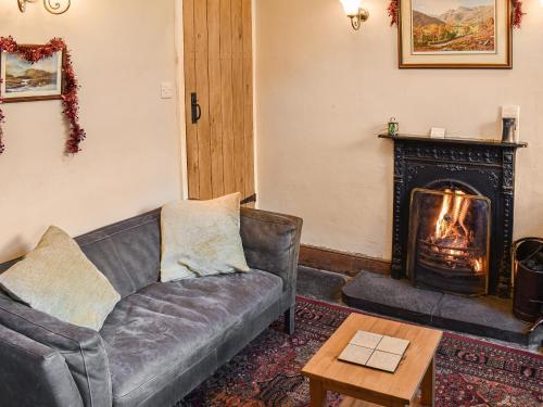 een woonkamer met een bank en een open haard bij Lingmoor View in Ambleside