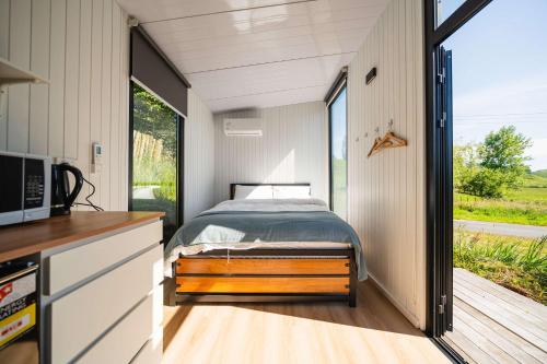 een slaapkamer in een tiny house met een bed bij Stour Cabin by Tiny Away in Huiroa