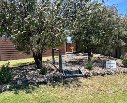 a garden with a tree and a sign in the grass at The Cosy Bungalow in Portarlington
