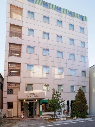 a large white building with windows on a street at Hotel Welcome Matsumoto in Matsumoto