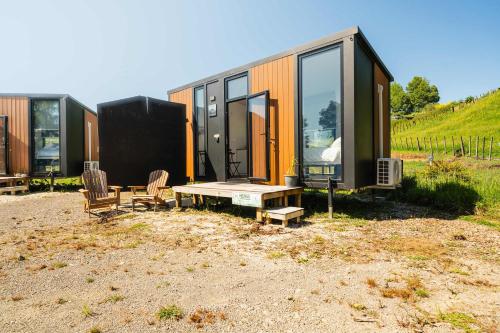 een tiny house met een picknicktafel en twee stoelen bij Henge Cabin by Tiny Away in Huiroa
