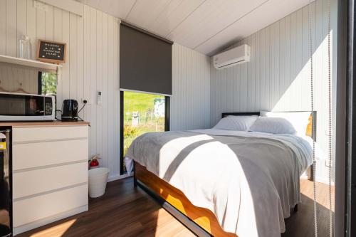 een slaapkamer met een bed en een keuken met een magnetron bij Henge Cabin by Tiny Away in Huiroa