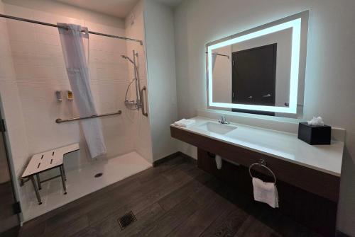 Un baño con lavabo y ducha con espejo. en Wingate by Wyndham Austin North, en Austin