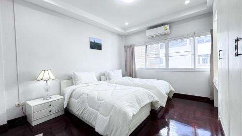 a white bedroom with two beds and a window at Blissful Heaven Residence at BTS Phromphong Emdistrict Shopping Area in Bangkok