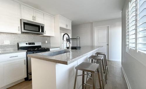 a kitchen with white cabinets and a counter with stools at Normandie Good Vibes Only in Los Angeles