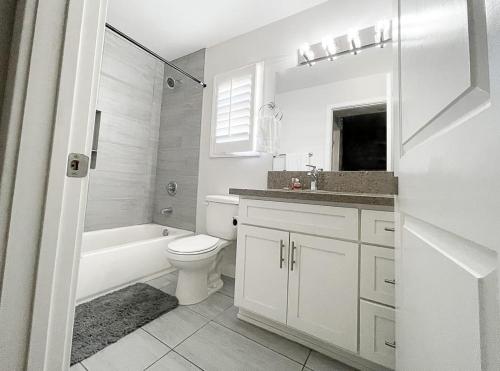 a white bathroom with a toilet and a tub and a sink at Normandie Good Vibes Only in Los Angeles