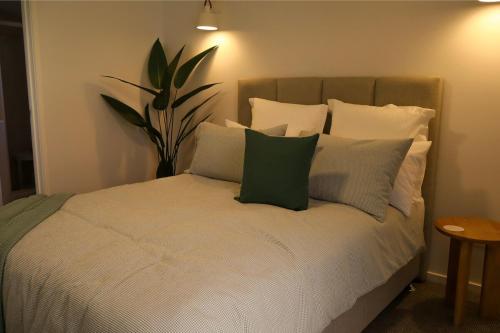 een bed met witte kussens en een plant erop bij Beach Street - LJHooker Yamba in Yamba
