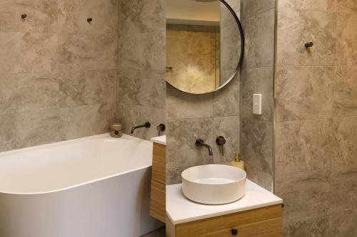 een badkamer met een witte wastafel en een spiegel bij Beach Street - LJHooker Yamba in Yamba