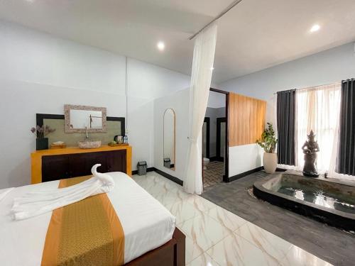 a bedroom with a bed and a tub in a room at Isyana's Family Suites Batur View by EPS in Kubupenlokan