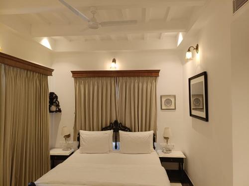 a bedroom with a bed with white sheets and curtains at The Anthill in Bolpur