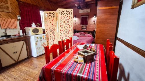 Una cocina con una mesa y sillas rojas y una cocina con estufa. en Cabaña 'Te para Tres' Merlo San Luis, en Merlo