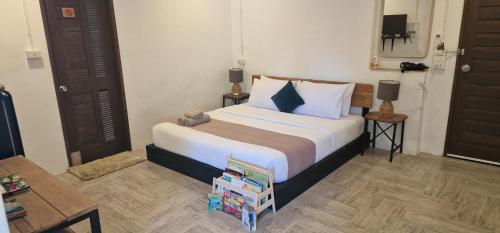 a bedroom with a bed with a pile of books at Kingfisher House in Sangkhla Buri