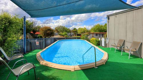 アーミデールにあるHighlander Van Villageの大きなスイミングプール(椅子、青いパラソル付)