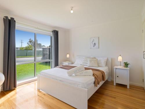 een witte slaapkamer met een bed en een groot raam bij Baravi Breeze Retreat in Safety Beach