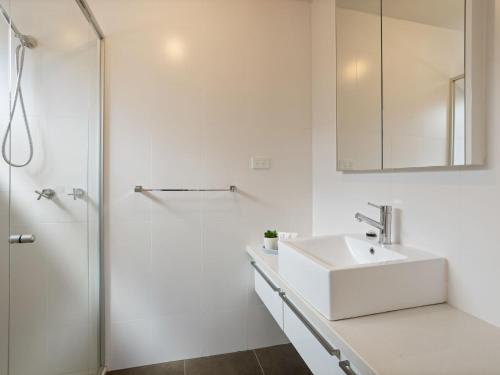 een witte badkamer met een wastafel en een douche bij Baravi Breeze Retreat in Safety Beach