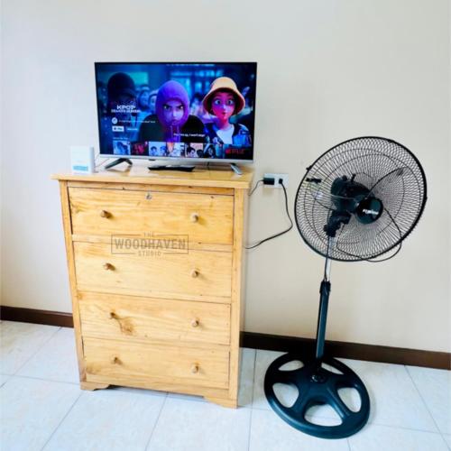 Ein Fan sitzt neben einer Kommode mit einem Fernseher. in der Unterkunft Spacious Studio Unit at Albergo Residences Baguio in Baguio City