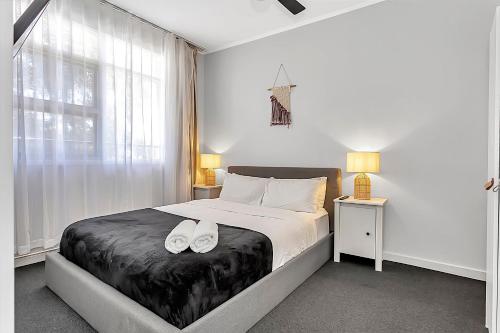 a bedroom with a bed with two white shoes on it at Walk to Beach And Cafes Near City And Airport in West Beach
