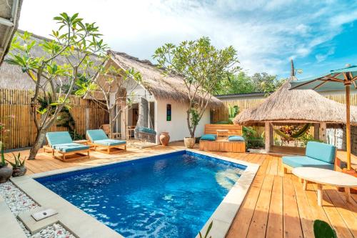 een zwembad in een achtertuin met stoelen en een huis bij Villa Satu Cinta in Gili Air