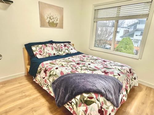 een slaapkamer met een bed en een raam bij Private Entire Guest Suite, 1 min to bus stops to Downtown and major attractions in Vancouver