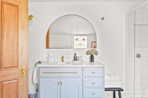 een badkamer met een witte wastafel en een spiegel bij The Countess in Launceston