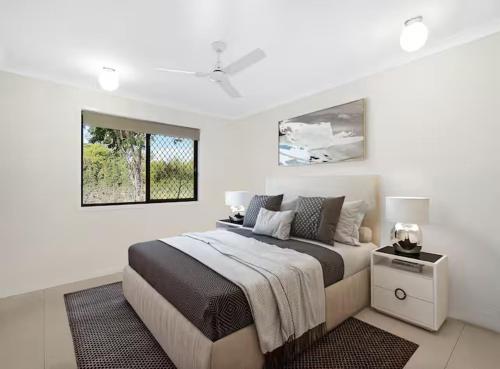 a white bedroom with a large bed and a window at 20 Min to Brisbane, Walk to Train, Modern 2BR in Goodna