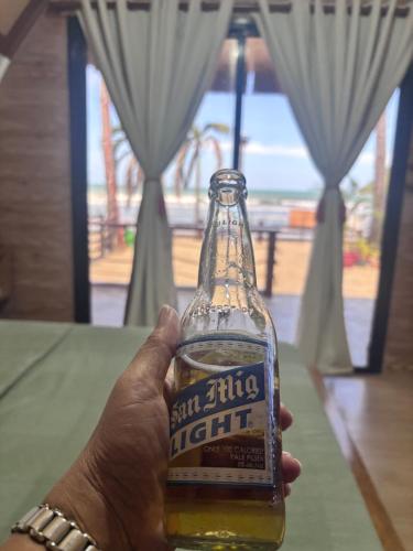 een persoon houdt een fles bier vast bij Kubotique Beachfront Staycation in El Nido