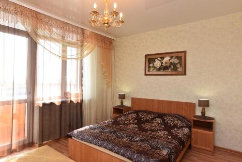 エカテリンブルクにあるApartment Domashny Uyut na Malysheva 4Bのベッドルーム1室(ベッド1台付)、シャンデリア付きの窓が備わります。