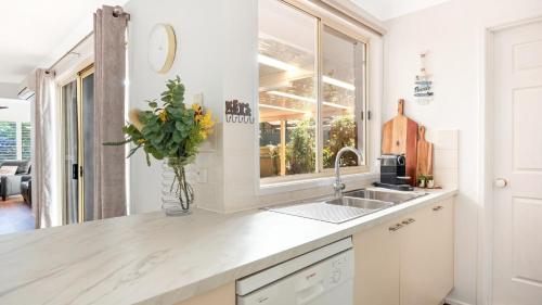 una cocina con fregadero y un jarrón de flores en La Playa, en Myola