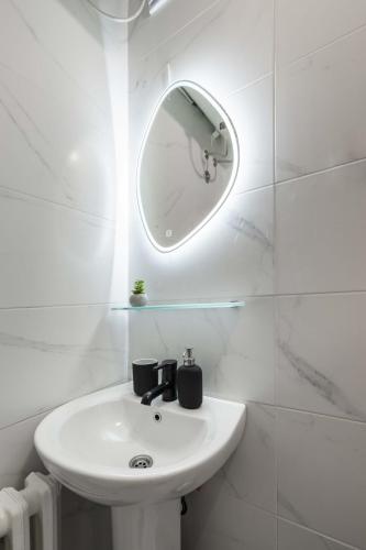 a white bathroom with a sink and a mirror at Old City Rooms in Novi Sad