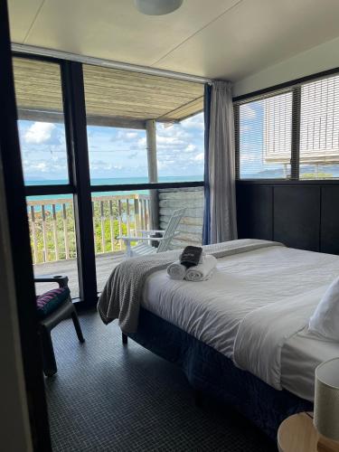 a bedroom with a large bed and a balcony at Stanmore Bay Log Cabin - short walk to beach in Stanmore Bay