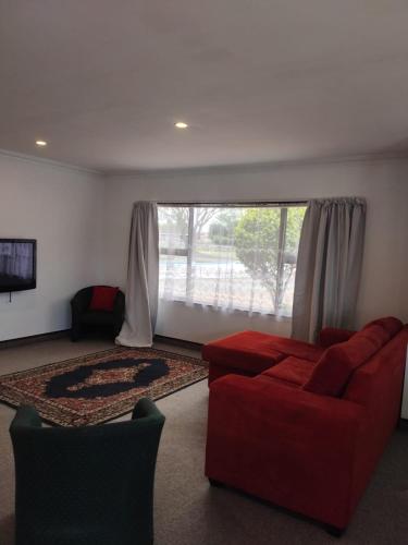 a living room with a red couch and a large window at Napier Nest Motel in Napier